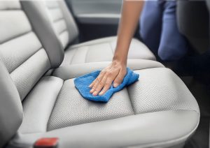 Someone cleaning their car seat with a microfiber cloth